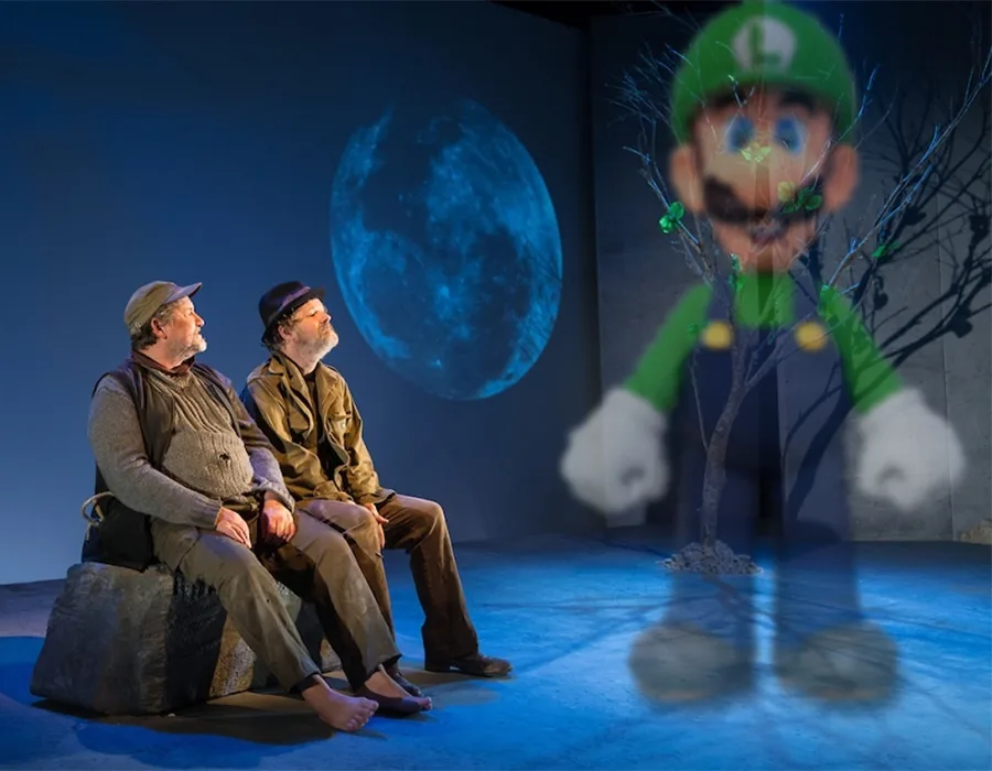Two men sit on a rock under a large blue moon, looking toward a translucent, ghostly Luigi from Mario games who appears to…