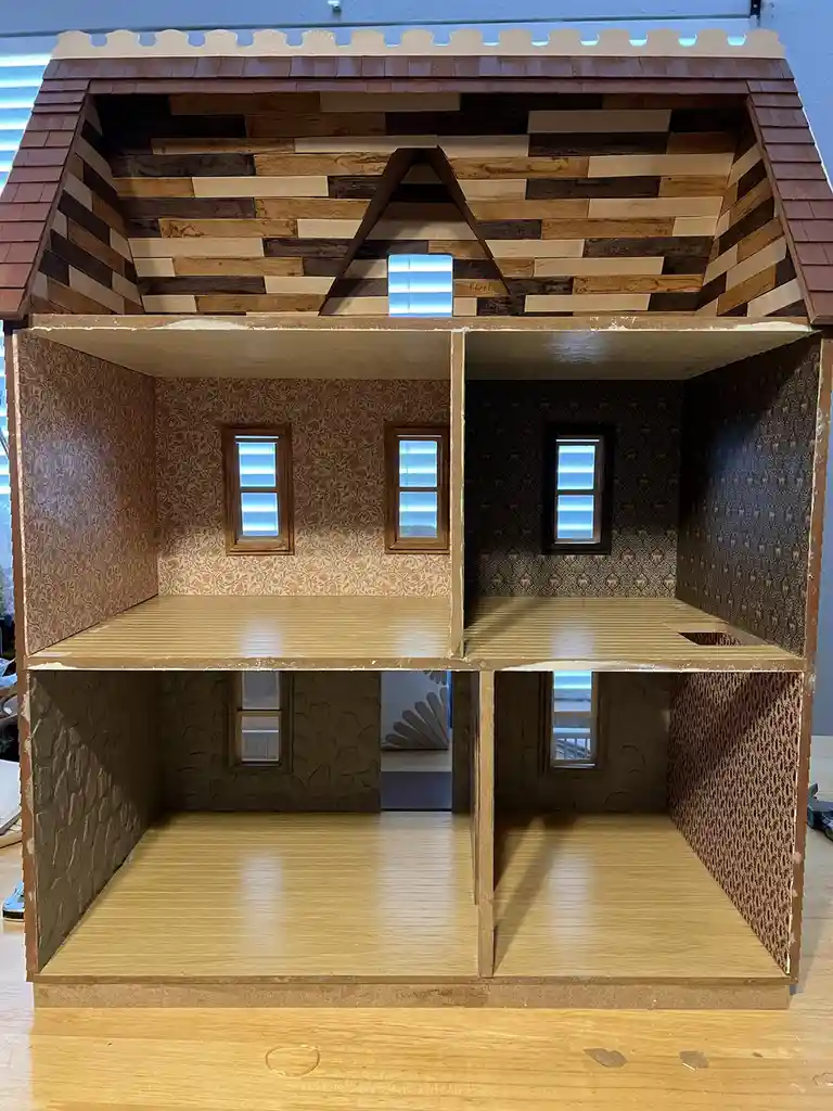 A handmade dollhouse with three floors and detailed wallpaper, windows, and a wooden roof, with the text 'foundation 23'…