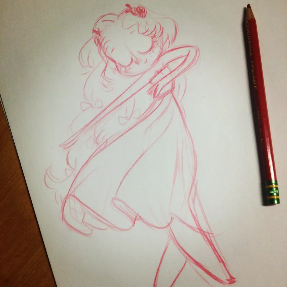A red pencil sketch on white paper depicts a stylized anime girl with pigtails and a bow, drawn in loose red pencil lines. A…