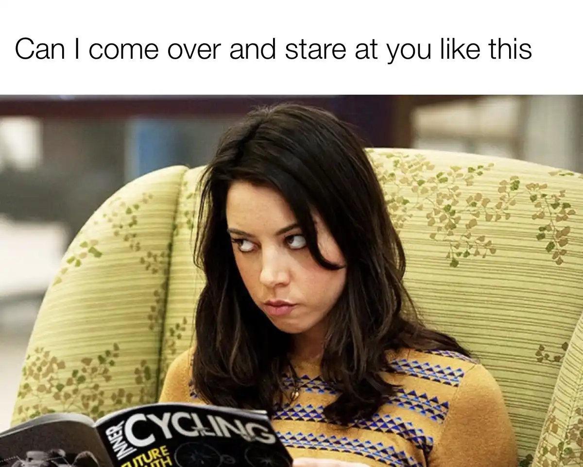A woman with dark hair sits in a patterned green armchair, holding a magazine titled 'CYCLING' and staring intently off to…