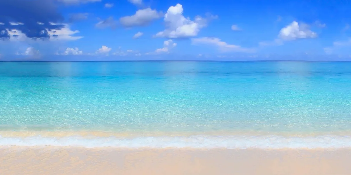 A serene tropical beach scene with turquoise water, white sand, and a blue sky with scattered clouds. Overlaid text reads…