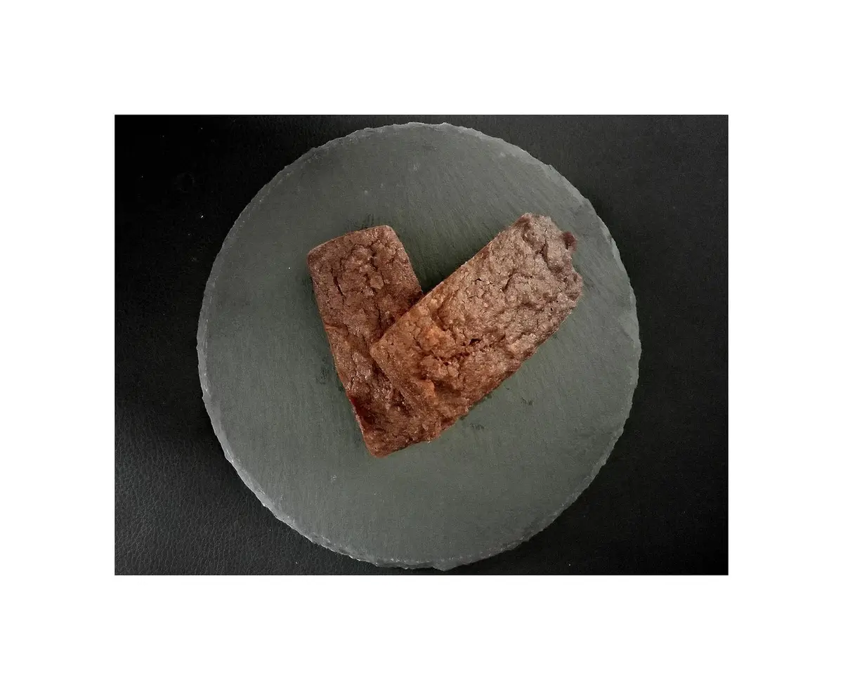 Two rectangular brownies are arranged on a round grey slate plate to visually form a heart shape, set against a dark…