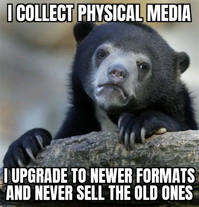 A black bear with a confused, slightly disappointed expression rests its paws on a log. The text overlaid in bold white…