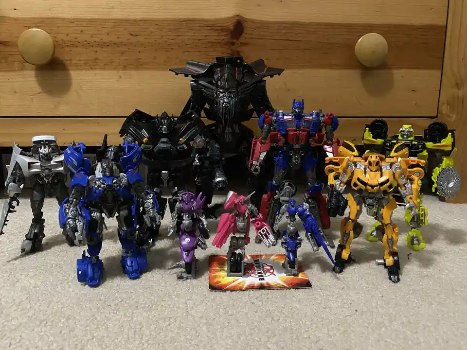 A collection of various Transformers action figures, including Optimus Prime, Bumblebee, and Megatron, are arranged on a…