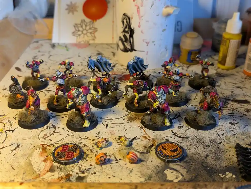 A collection of painted fantasy miniatures, resembling goblins or orcs in Halloween-themed attire with pumpkins and skulls…