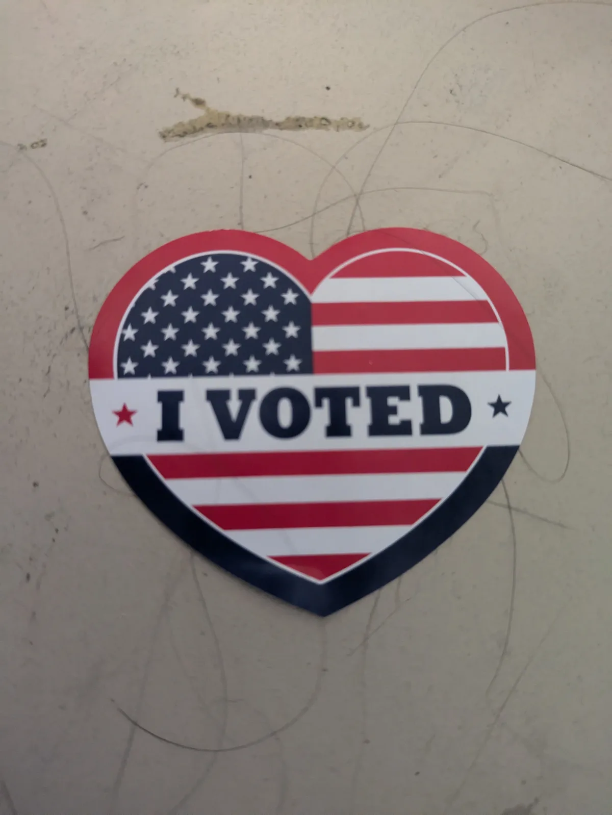 A heart-shaped sticker featuring the American flag design with stars and stripes, displaying the text 'I VOTED' across the…