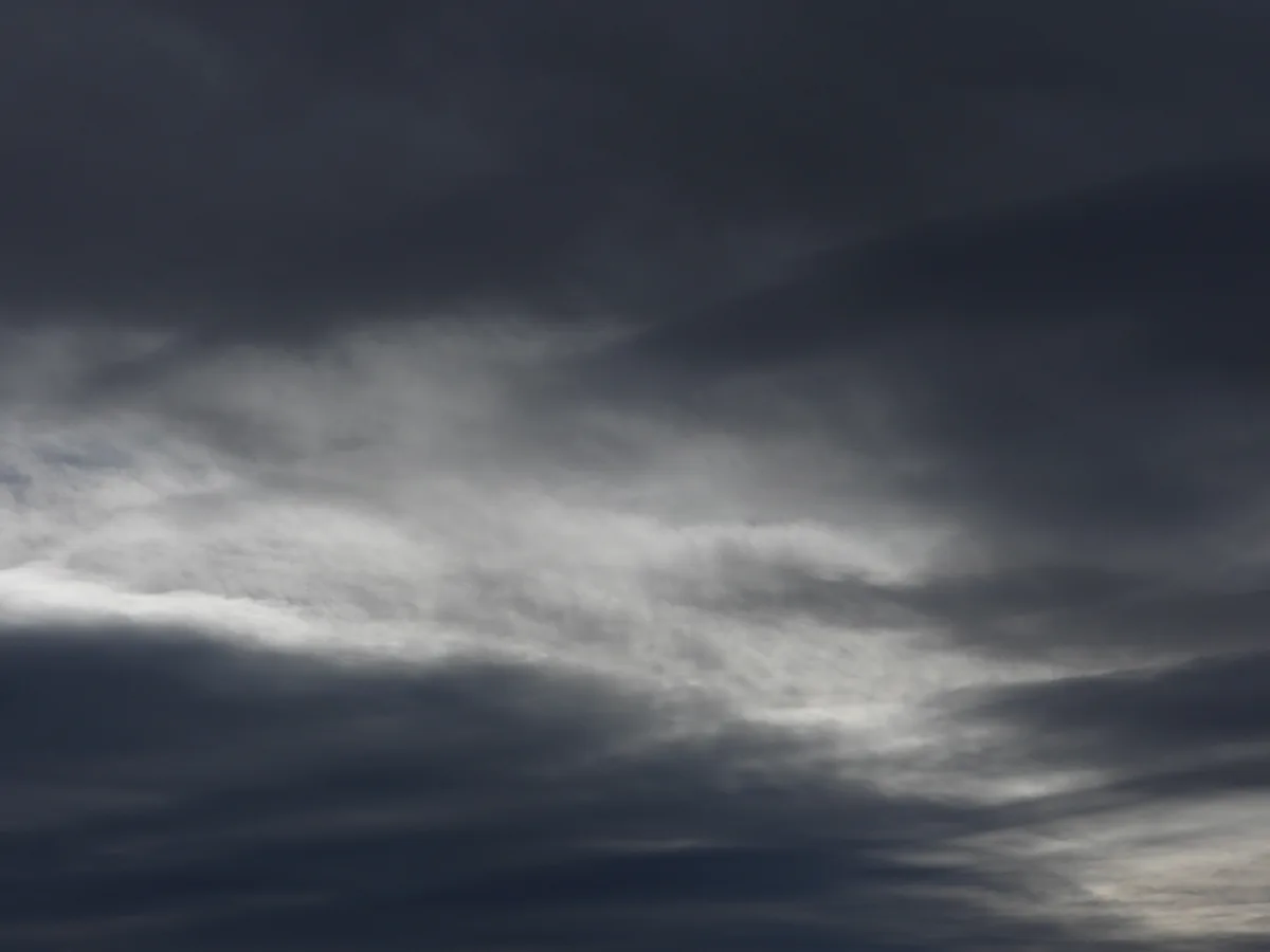 A dark, moody sky filled with swirling gray and white clouds, with no people or objects visible. The overlaid text reads…