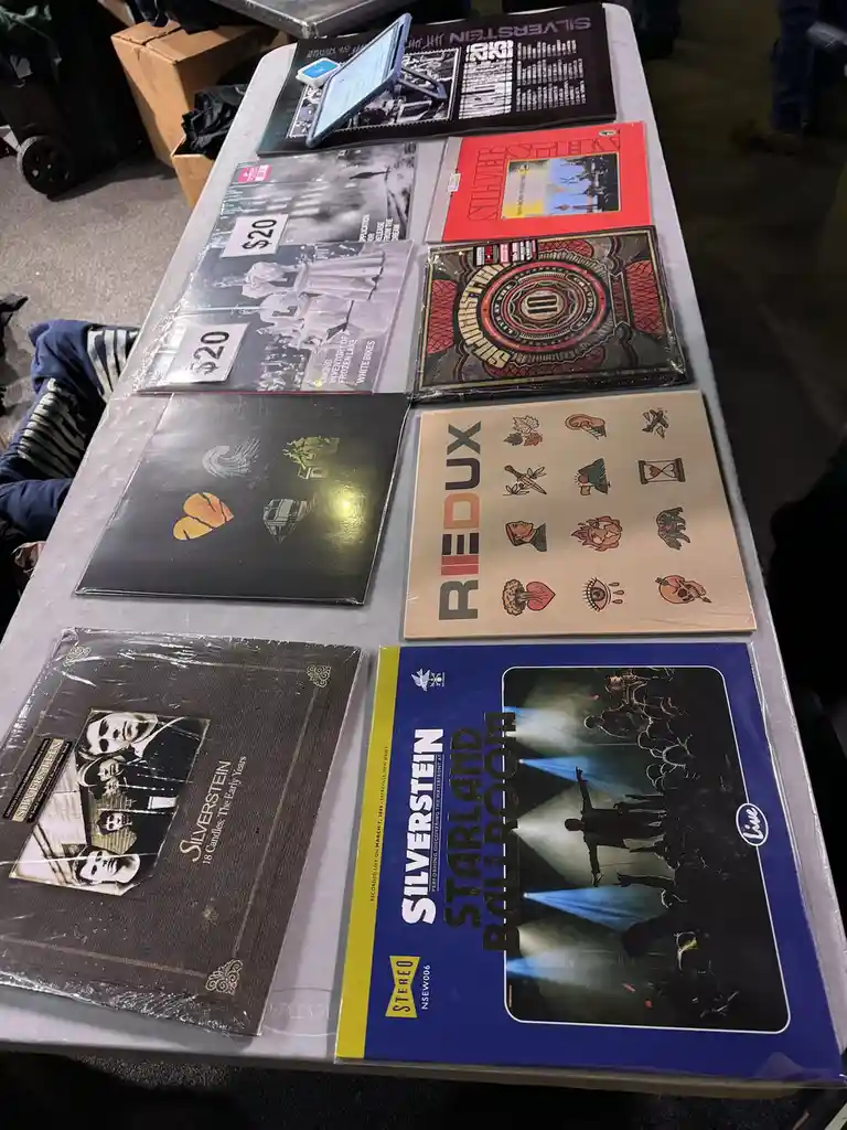 A table displays multiple sealed vinyl records by the band Silverstein, including albums like '18 Candles: The Early Years'…
