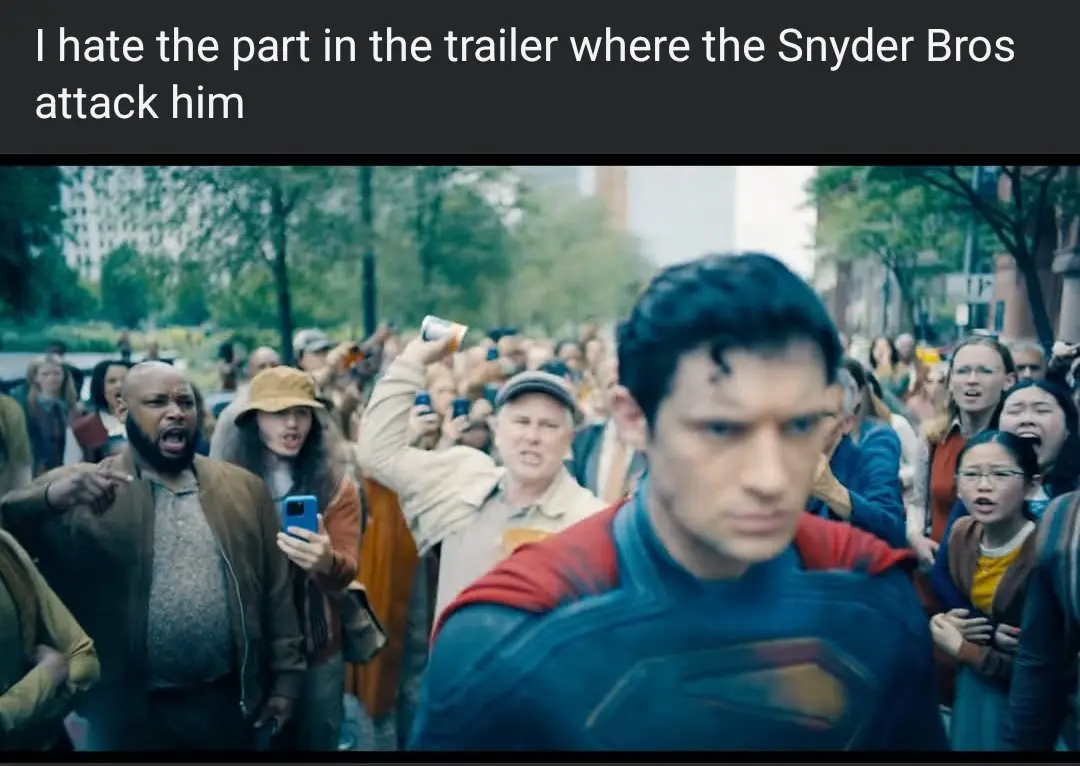 A still from a superhero movie shows Superman in his blue and red suit looking forward with a serious expression, surrounded…