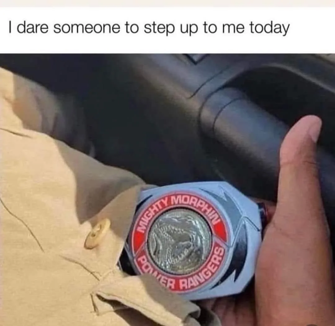 A close-up image shows a person's hand holding a white Mighty Morphin Power Rangers Morpher, which features a silver dragon…