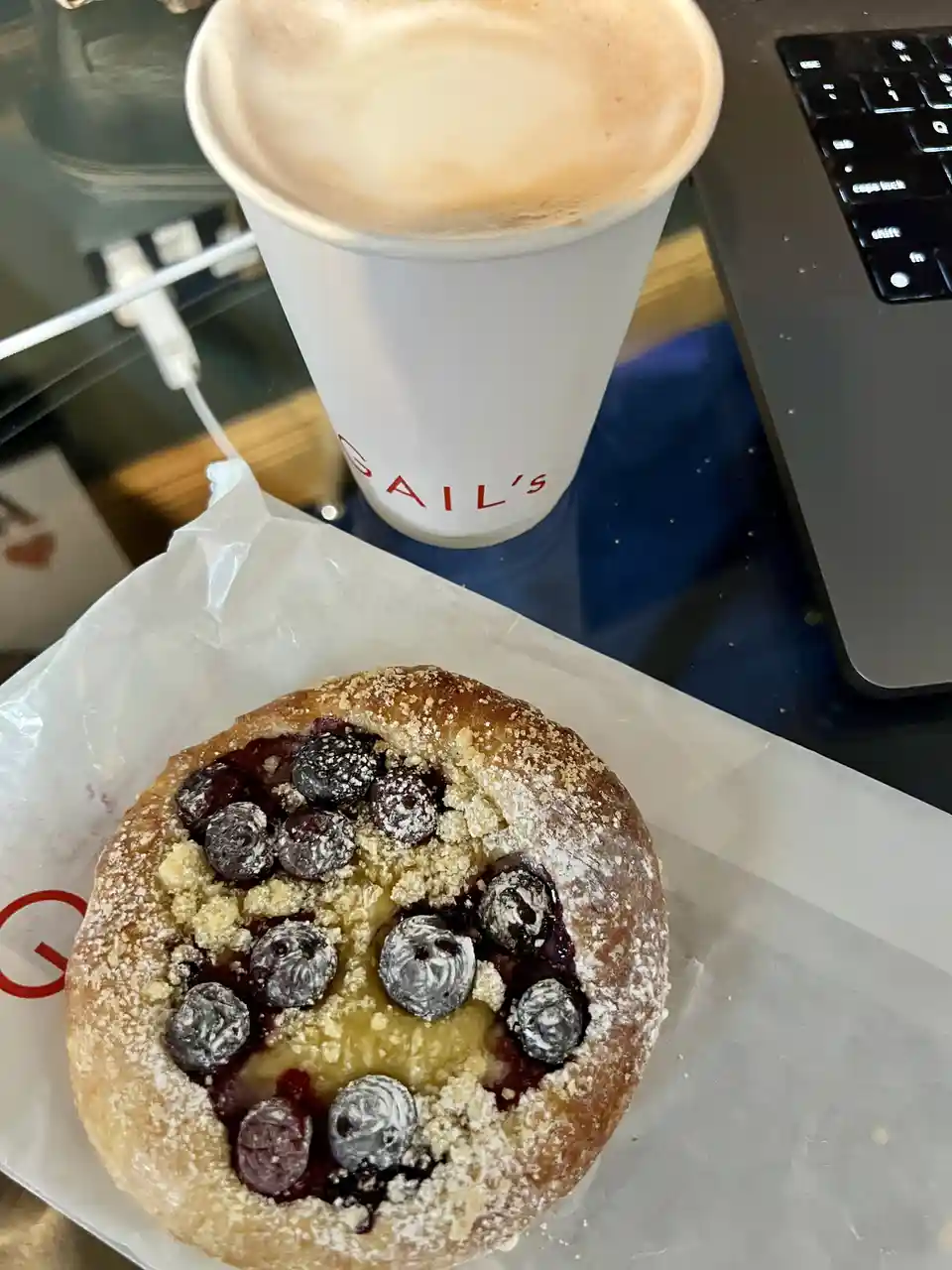 A close-up photo shows a blueberry-filled pastry on white paper, with blueberries arranged to form a smiley face. Beside it…