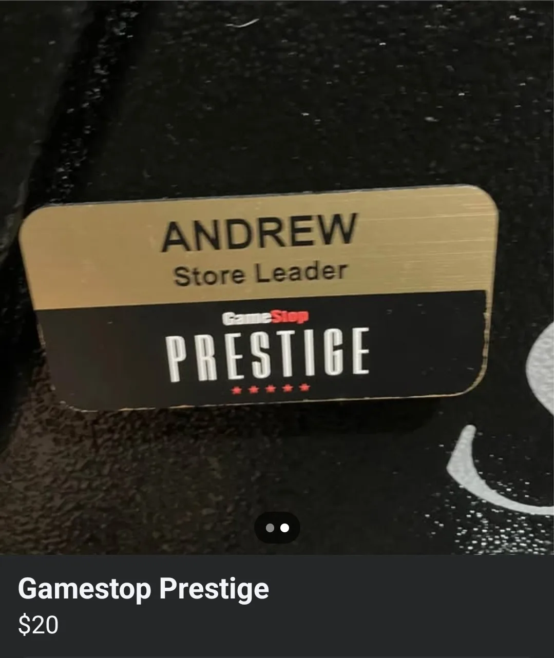 A close-up of a GameStop employee name badge showing 'ANDREW' and 'Store Leader' above the 'GameStop PRESTIGE' title with…