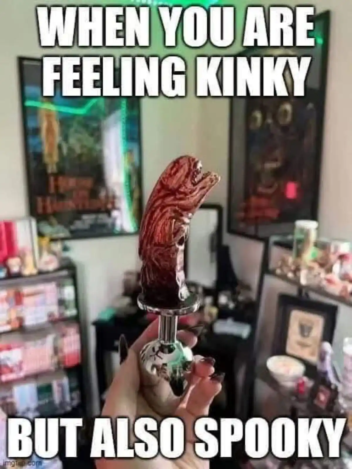 A hand holds a smoking pipe with a grotesque, alien-like creature head, set against a backdrop of horror-themed decor…
