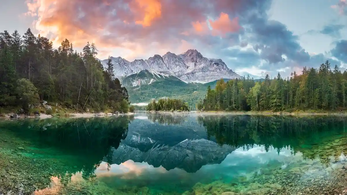 Standing atop the Austrian border, Zugspitze, the highest peak in Germany, majestically towers 10,000 feet above Eibsee…
