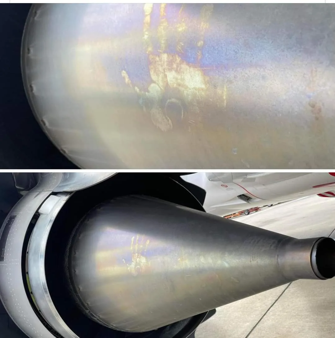The image shows a close-up of a jet engine's exhaust cone with a visible handprint on its metallic surface, likely from a…