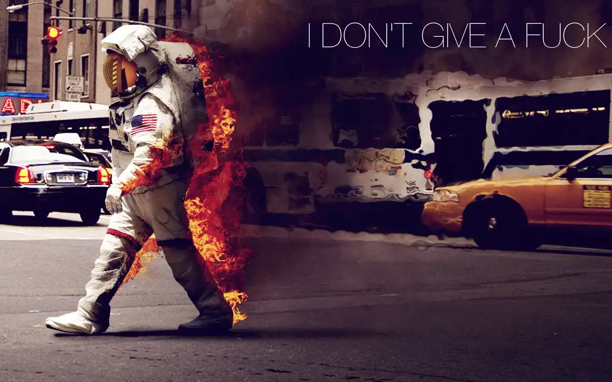 An astronaut in a white spacesuit with an American flag patch is walking across a city street, visibly on fire from the…