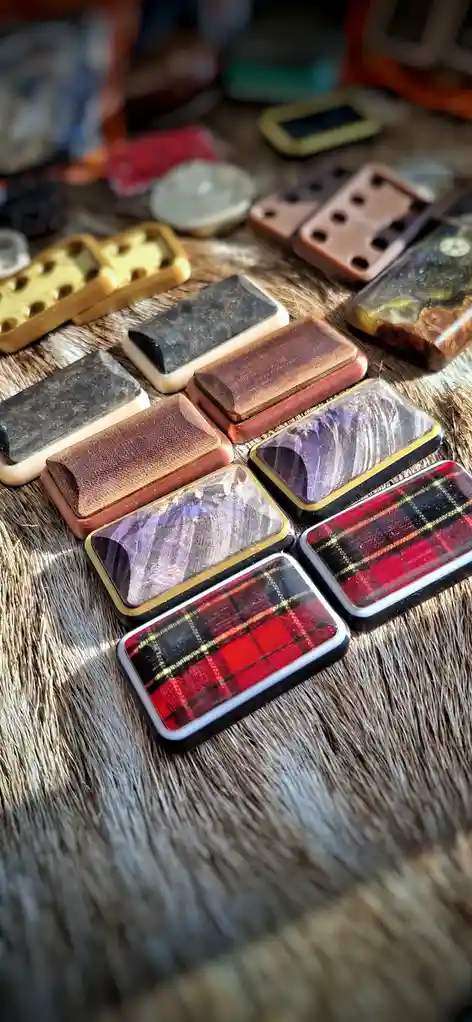 A collection of rectangular, handmade-looking objects with various textures and patterns, including plaid fabric, wood…