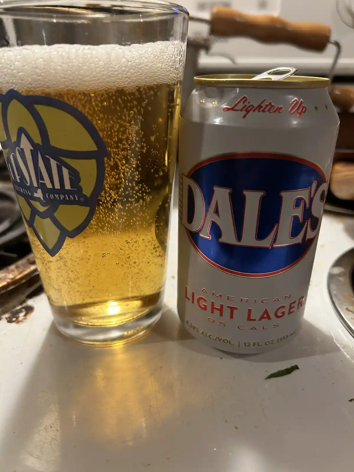 A can of Dale's American Light Lager, with 'Lighten Up' written on top, sits next to a glass of beer from the 'Coastal…