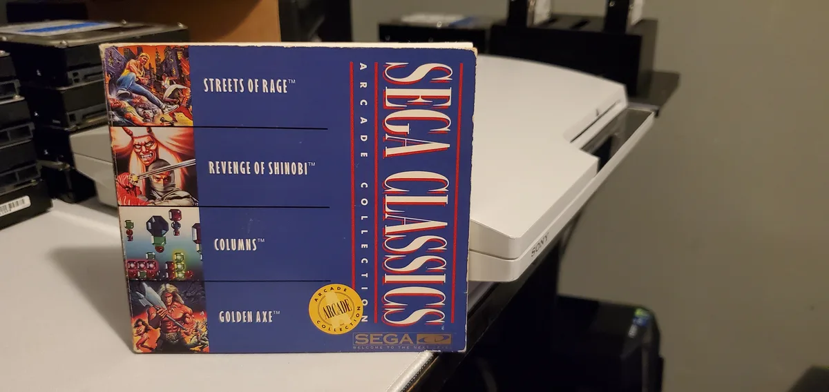 A blue Sega Classics Arcade Collection game box featuring Streets of Rage, Revenge of Shinobi, Columns, and Golden Axe is…