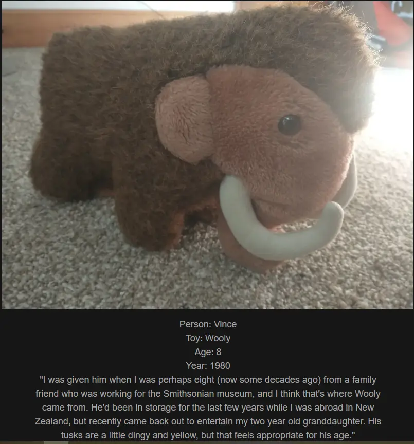 A brown, fuzzy plush mammoth toy with curved white tusks sits on a beige carpet. Overlaid text identifies it as 'Wooly', an…
