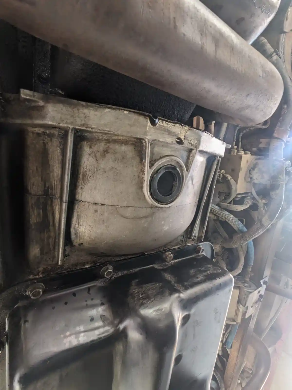 A close-up photo of a dirty, greasy engine component with a circular opening that resembles a face, overlaid with the text…