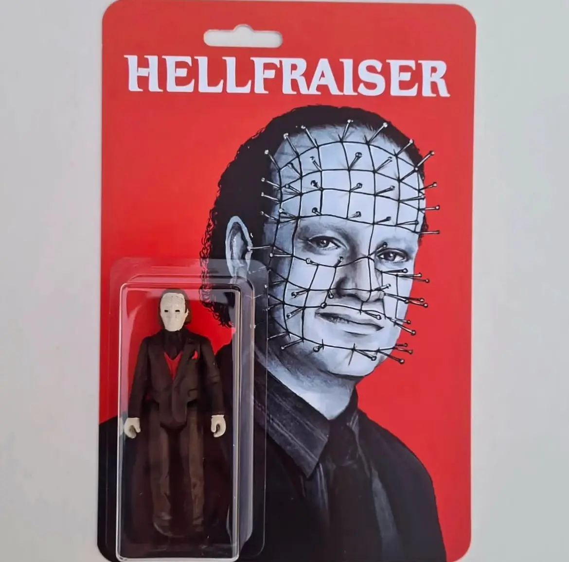 A toy package for a Hellraiser action figure features a large image of the character Pinhead with his face covered in pins…