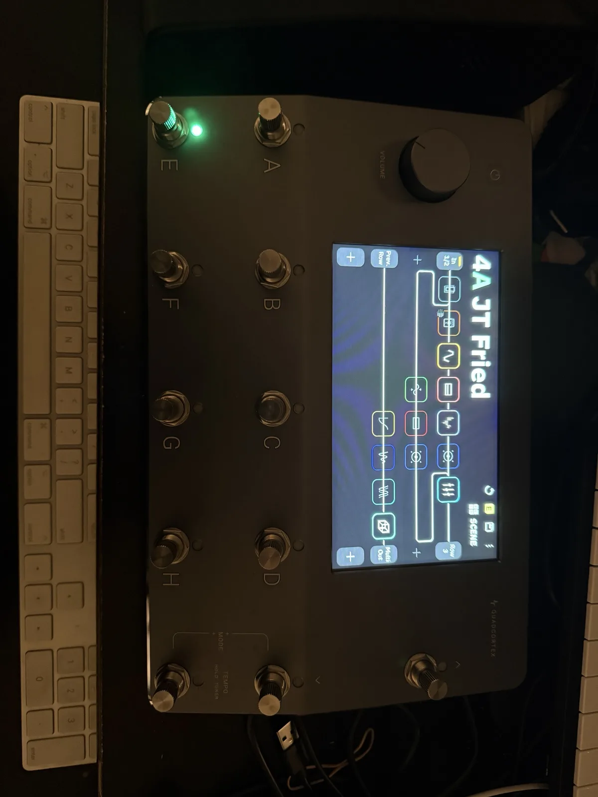 A close-up photo of a black Quad Cortex MIDI controller pedal with a lit screen displaying '4A JT Fried' and various…