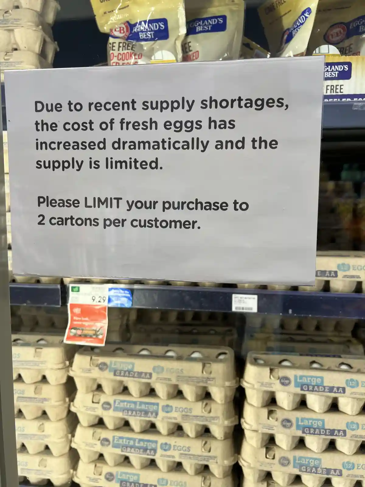A sign in a grocery store egg aisle states that due to supply shortages, egg prices have risen and supply is limited, asking…