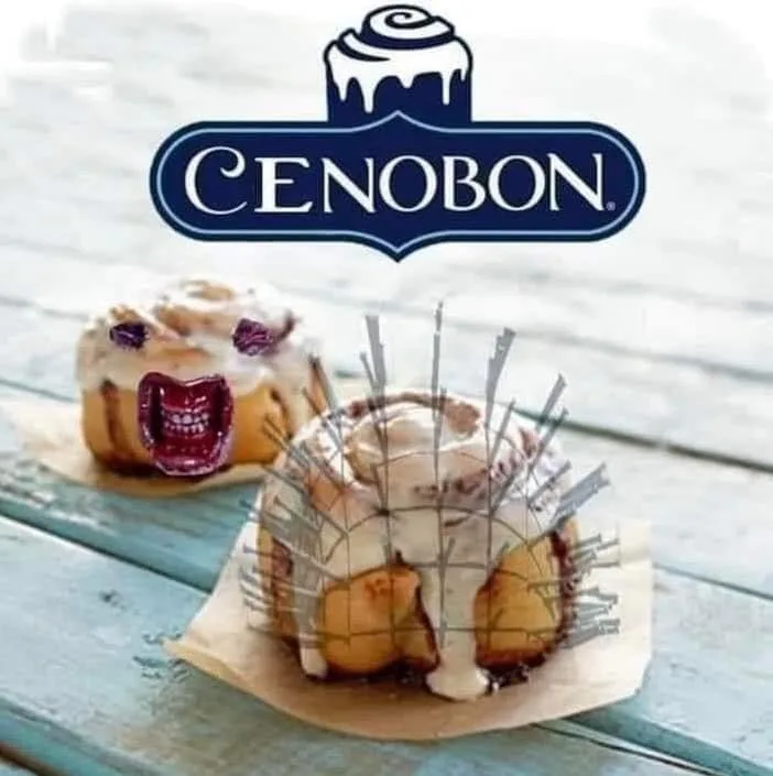 Two cinnamon rolls sit on a wooden surface, one with a cartoonish screaming face made of frosting and jelly, the other with…