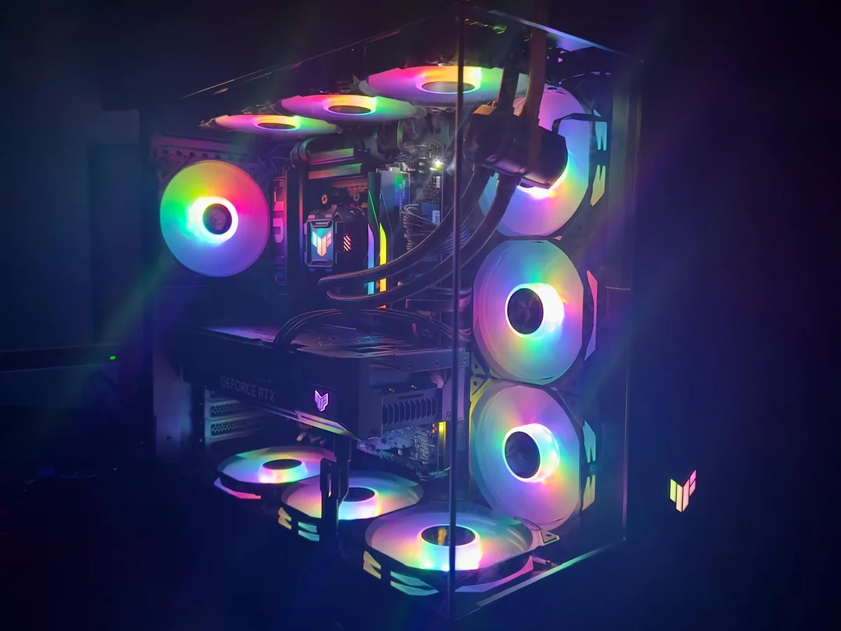 A high-end custom PC with a glass case, illuminated by multiple RGB fans glowing in rainbow colors, showcasing a GeForce RTX…