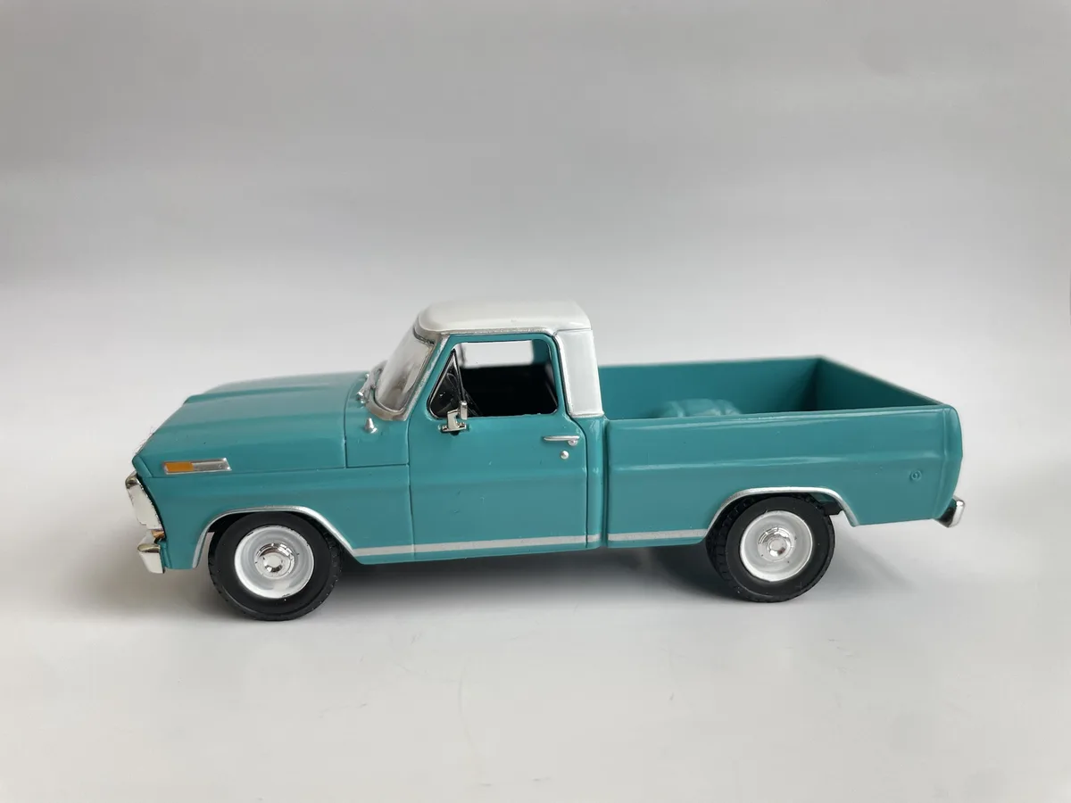A teal and white vintage-style toy pickup truck is shown in profile against a plain white background. The overlaid text…