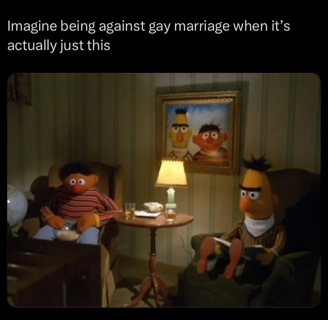 Two Muppet characters, Bert and Ernie, sit in armchairs in a dimly lit room with a small table between them holding drinks…