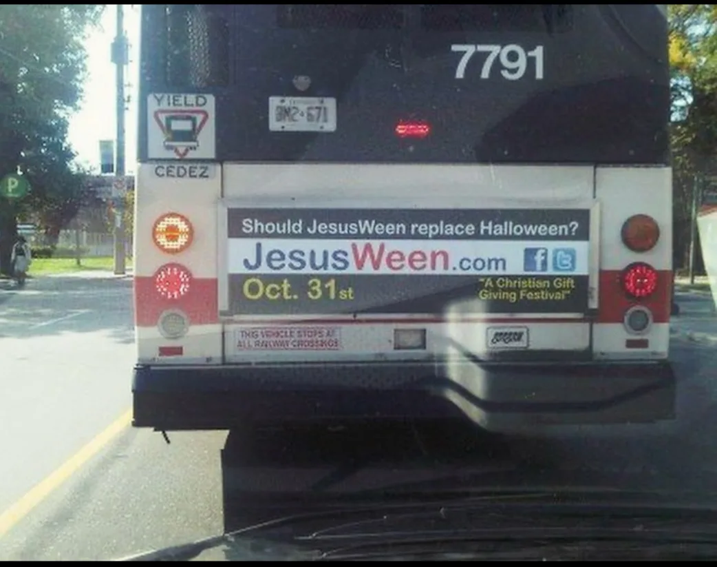 The back of a black and white bus with the number 7791, showing a large advertisement that asks 'Should JesusWeen replace…