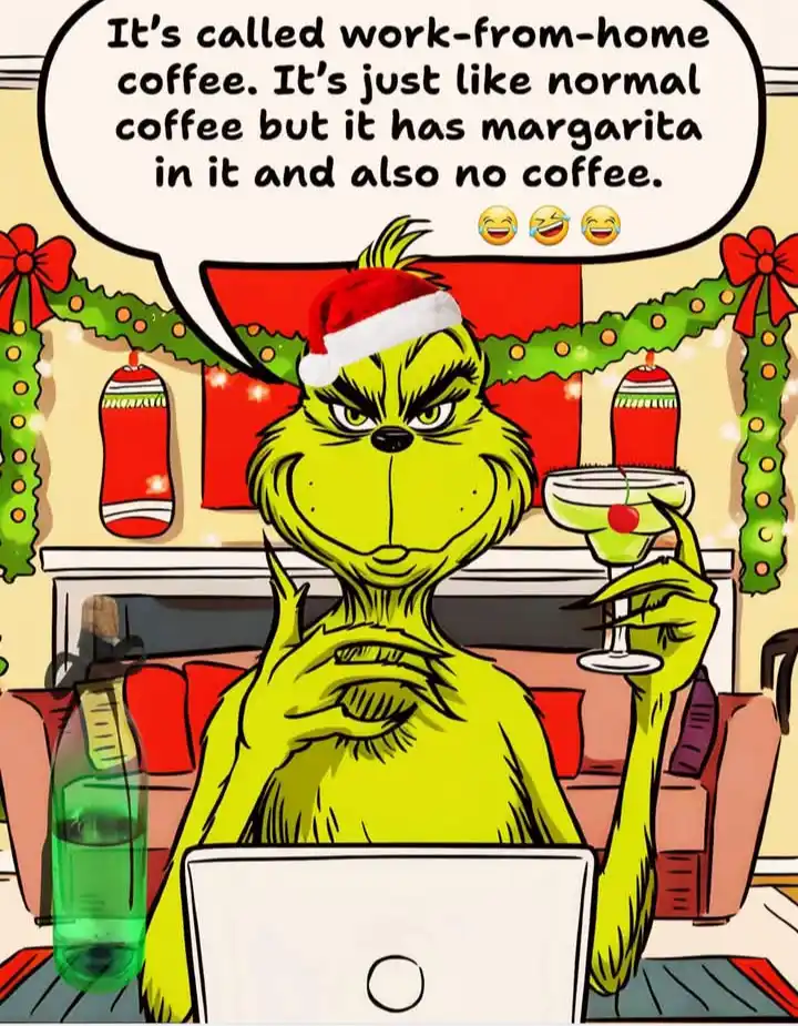 The Grinch, wearing a Santa hat and sitting in a Christmas-decorated room, holds a margarita while working on a laptop. A…