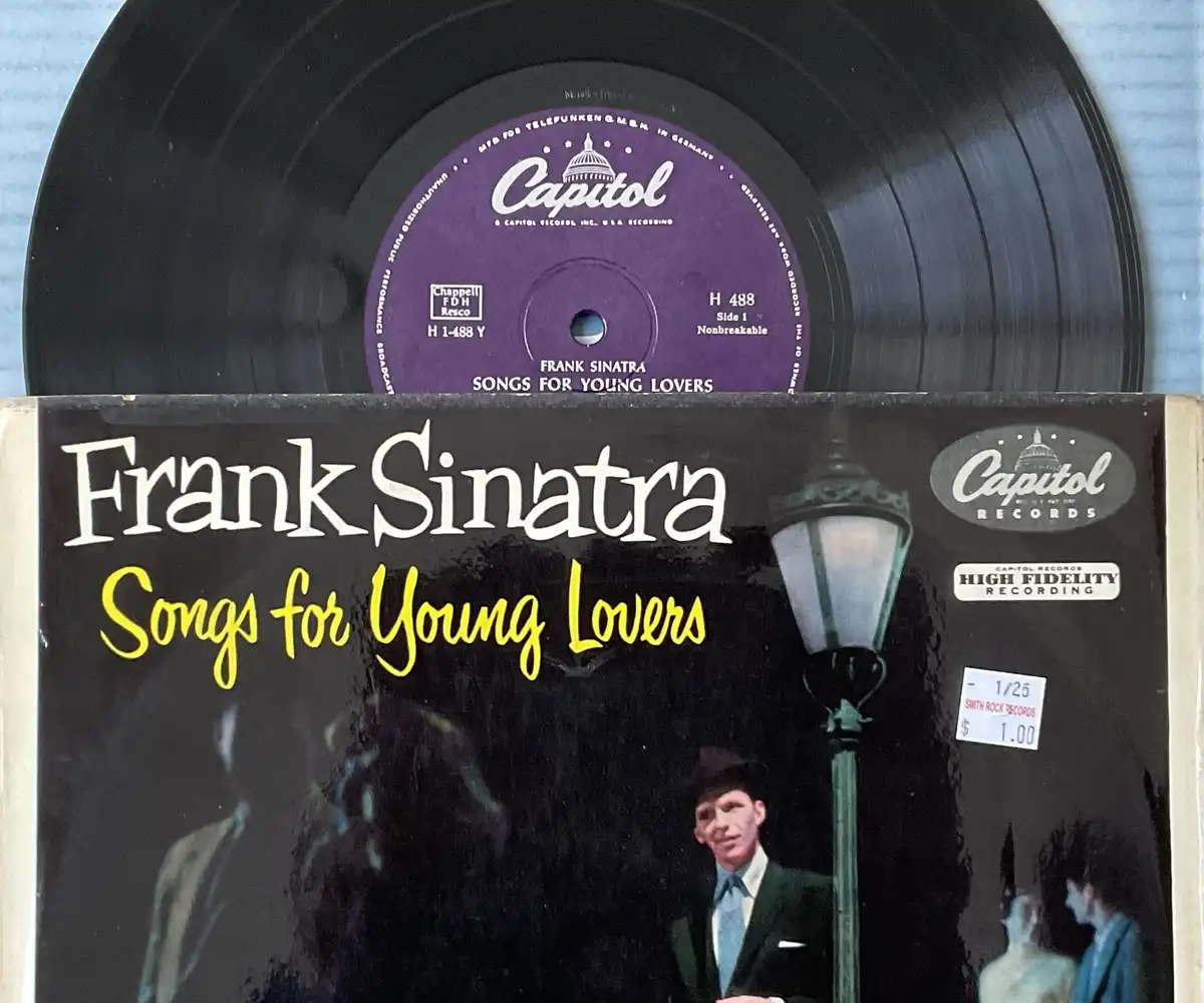 A close-up photo shows a Frank Sinatra vinyl record and its album cover for 'Songs for Young Lovers,' both featuring the…