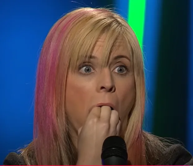 a woman with blonde hair streaked with pink is shown with a shocked expression, her eyes wide and her hand covering her…