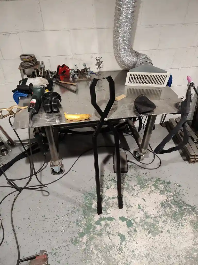 A metal workbench in a workshop is cluttered with tools like a grinder, clamps, and a welding torch, with a single ripe…