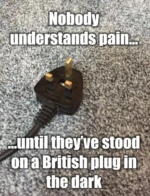 A close-up photo shows a black British three-pin electrical plug lying on a grey, textured carpet. White bold text is…