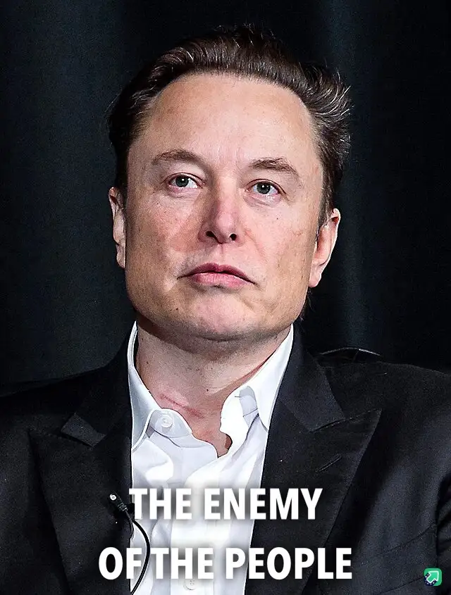 A close-up photo of Elon Musk wearing a black suit and white shirt, looking directly at the camera with a serious, slightly…