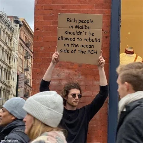 A man with curly hair and sunglasses holds up a cardboard sign that reads 'Rich people in Malibu shouldn't be allowed to…