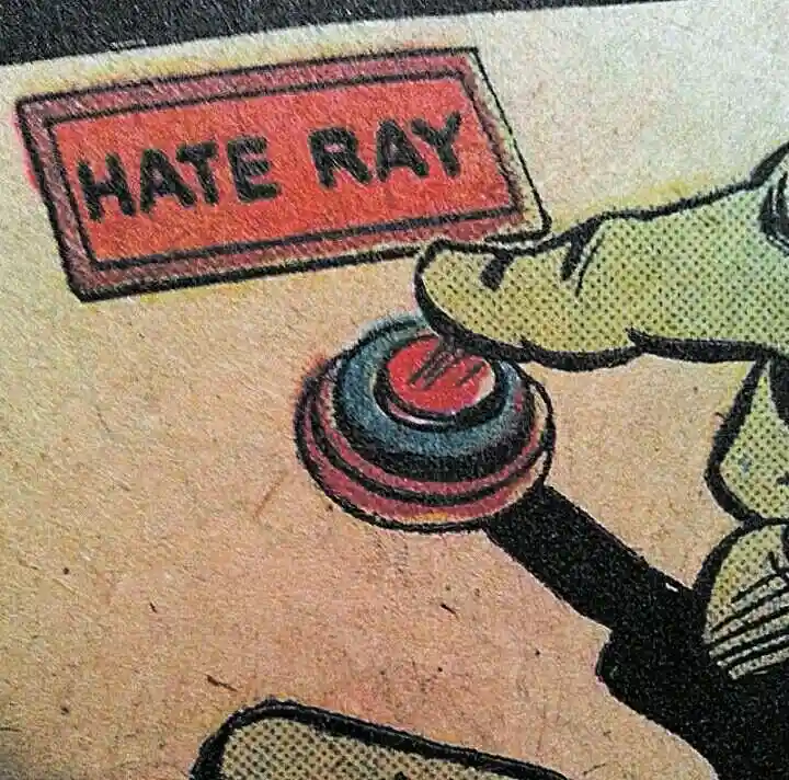 A vintage comic book panel shows a cartoonish green-skinned hand pressing a large red button labeled 'HATE RAY'. The image…