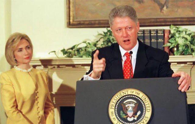 former president bill clinton stands at a podium with the presidential seal, gesturing emphatically while speaking, with his…