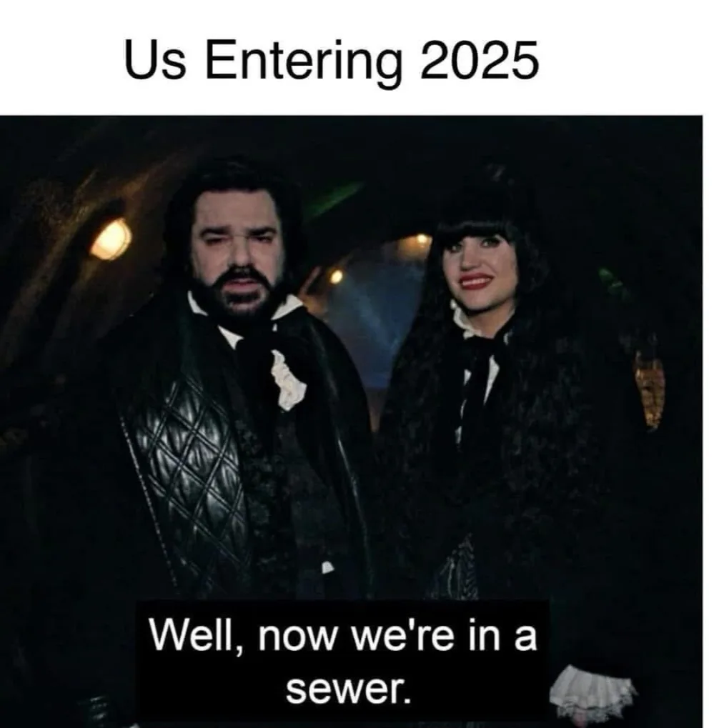 A man and woman in dark, gothic-style clothing stand in a dimly lit, tunnel-like setting. The man has a weary, resigned…