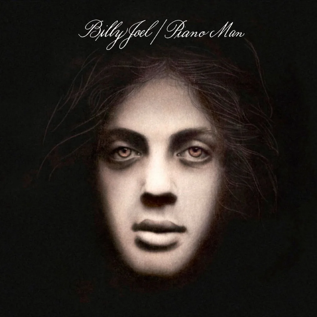 The image is the iconic album cover for Billy Joel's 'Piano Man,' featuring a close-up of a man's face with dark, smudged…