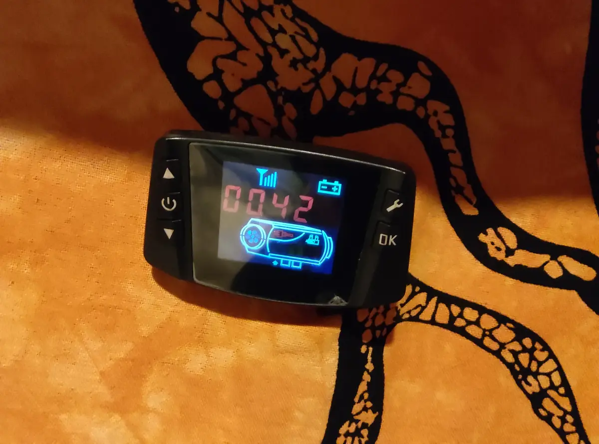 A black handheld electronic device with a lit screen displaying the number 0042 in red, surrounded by blue icons including a…