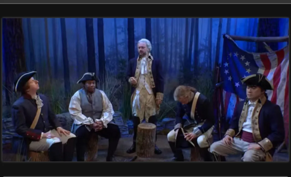 Five men in colonial-era American revolutionary uniforms sit or stand in a forest setting with an early American flag…