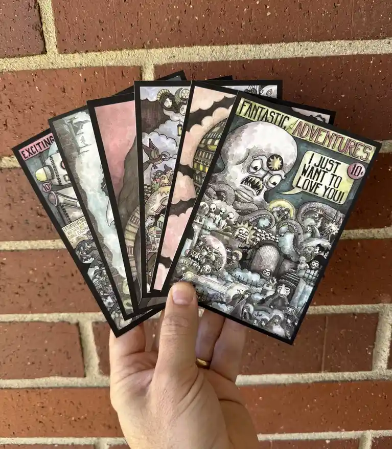 A hand holds a fanned-out set of illustrated cards against a brick wall. The visible card on the right is titled 'FANTASTIC…