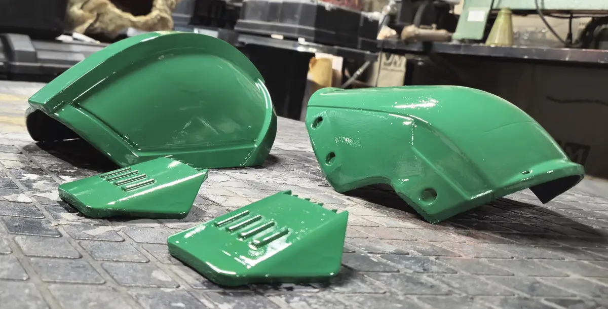 Four freshly painted green tractor parts, including two large curved panels and two smaller rectangular ones with slotted…
