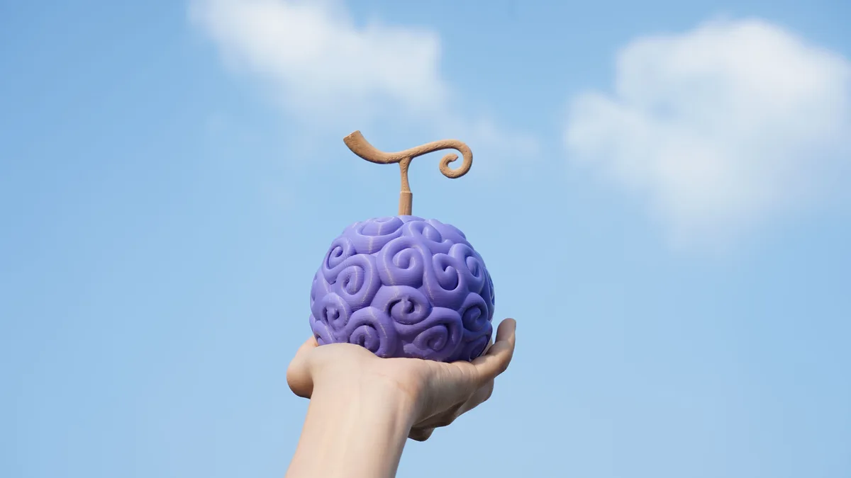 A hand holds a purple, brain-like fruit with a wooden stem against a blue sky with clouds. The overlaid text reads 'i found…