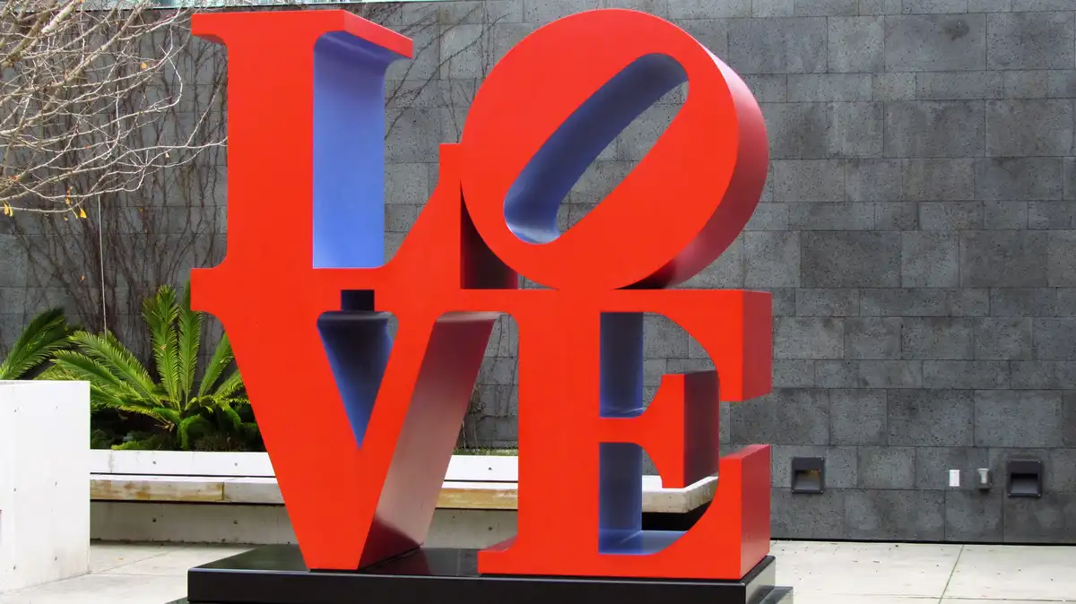 A large, red, three-dimensional sculpture spells out the word 'LOVE' in bold, block letters with blue interiors, standing…